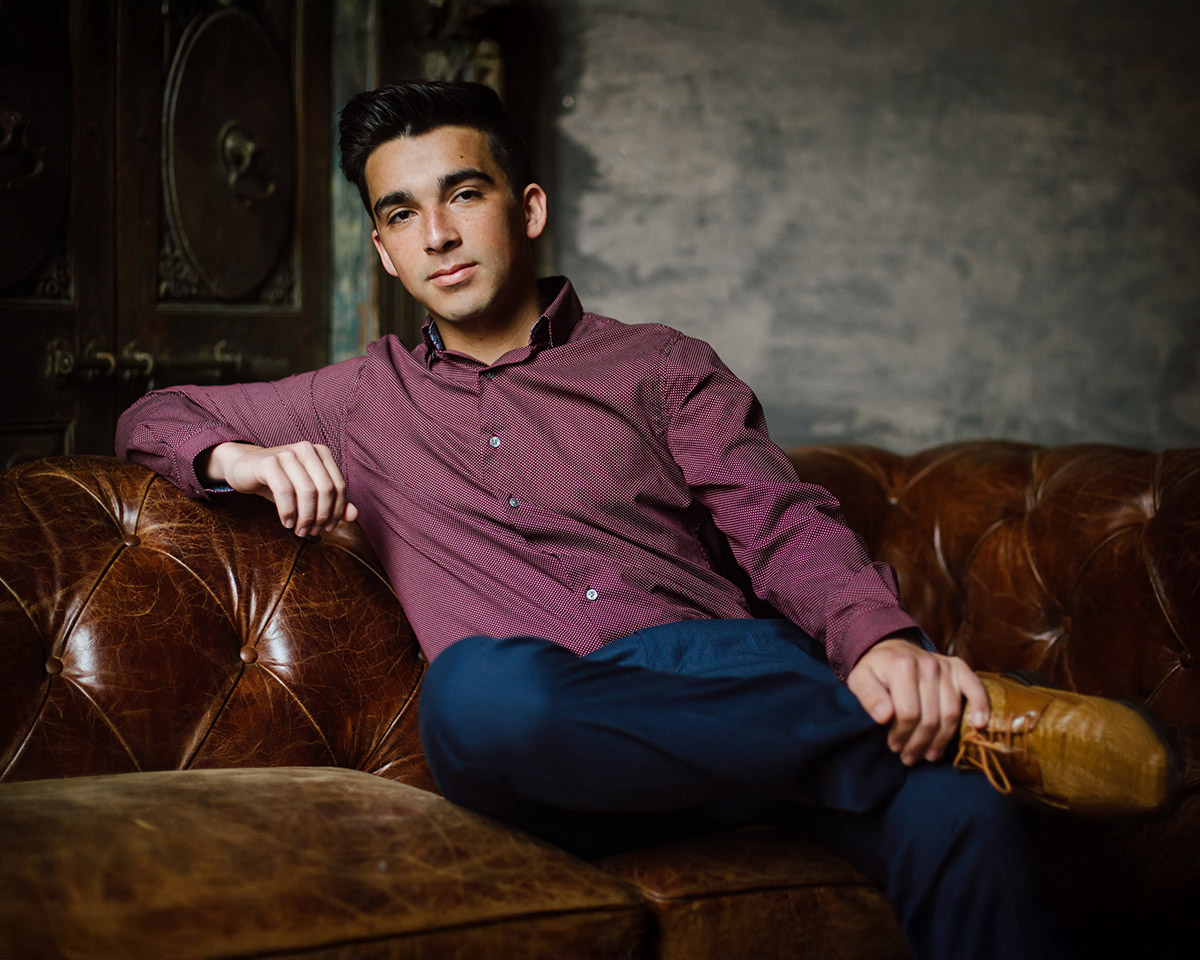 Senior hs boy photographed in studio on leather chair, relaxing